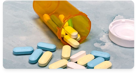 Colorful tablets spilling from an orange prescription bottle