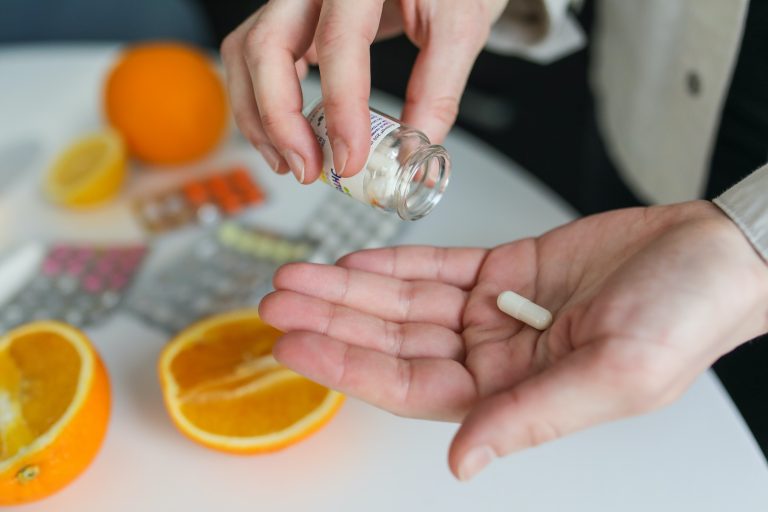 Person pouring a pill out into their hand from a bottle.